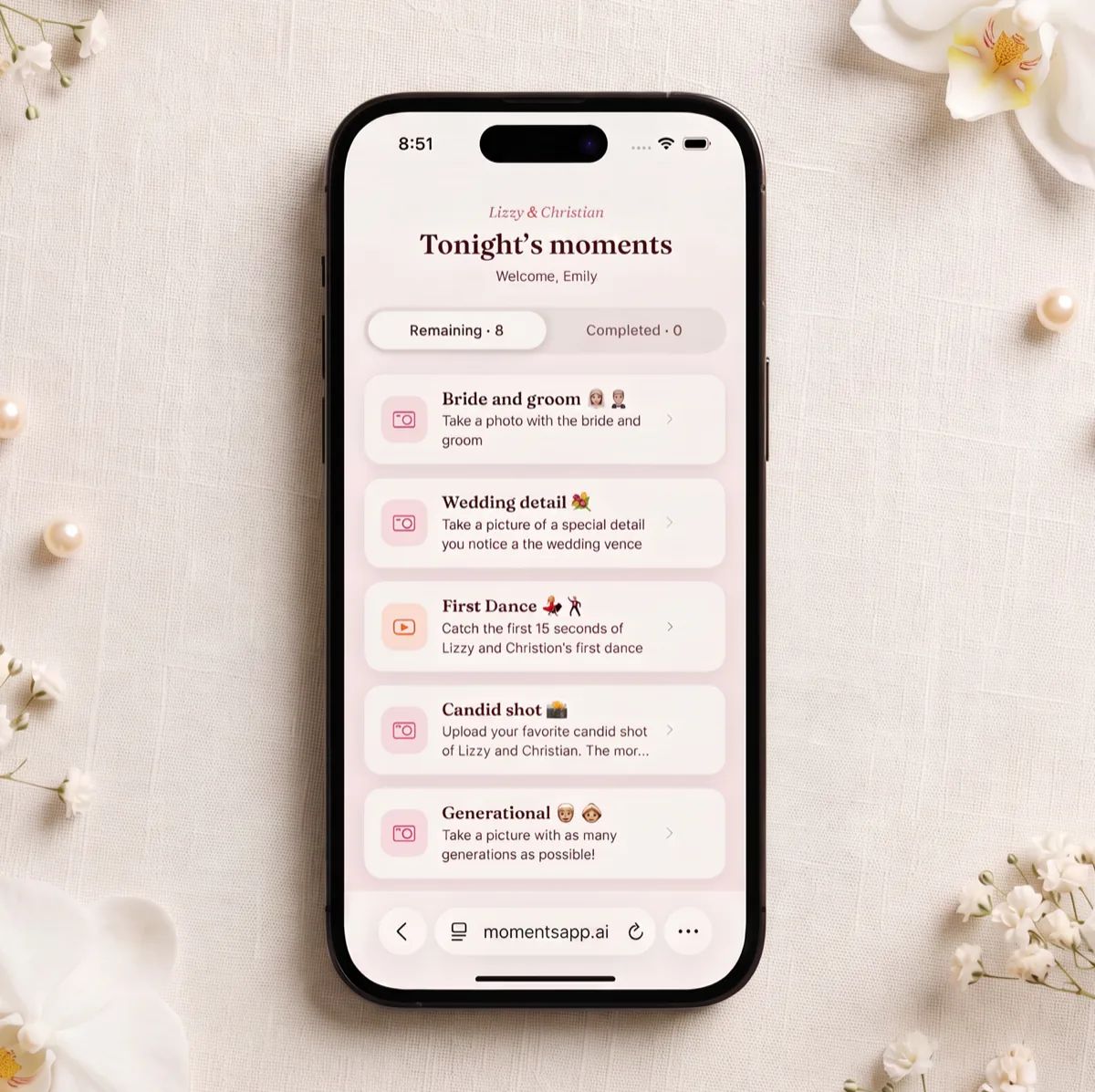 A phone on linen among orchids and pearls, showing Lizzy and Christian’s checklist of tonight’s moments: bride and groom, wedding detail, first dance, candid shot.
